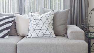 Sofakissen auf grauem Sofa und Vorhänge