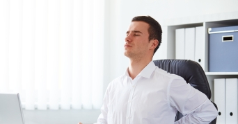 Lordosekissen Mann benutzt Lordosekissen gegen Rückenschmerzen