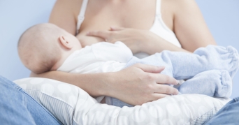 Stillkissen Frau stillt ein Baby mit einem Stillkissen