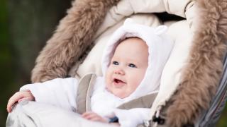 Kind sitzt glücklich auf einem Kinderwagen Kissen